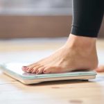 feet of a woman stepping on a weighing scale