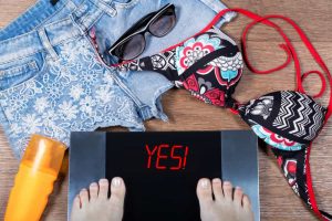 woman weights herself before summer vacation